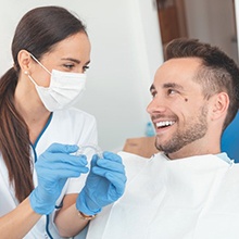 Smiling patient and dentist discussing the cost of Invisalign in Hampton 