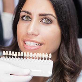 Woman's smile compared with tooth color chart