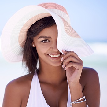 Woman with sun hat smiling at beach