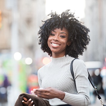 a lady smiling and standing in a city center