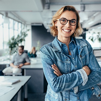 a businesswoman standing in an office with her arms crossed