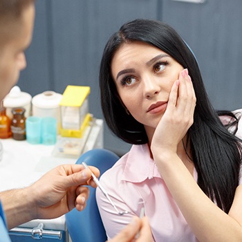 Woman holding jaw in pain at dentist office 