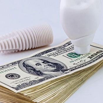 dental implant lying on top of a stack of cash