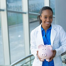 smiling dentist holding a pink piggy bank