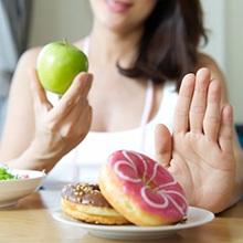 person choosing to eat apples instead of donuts 