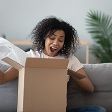 young woman excitedly opening a box 