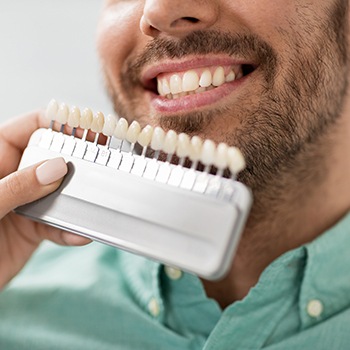 Dental assistant holding shade scale to patient's teeth