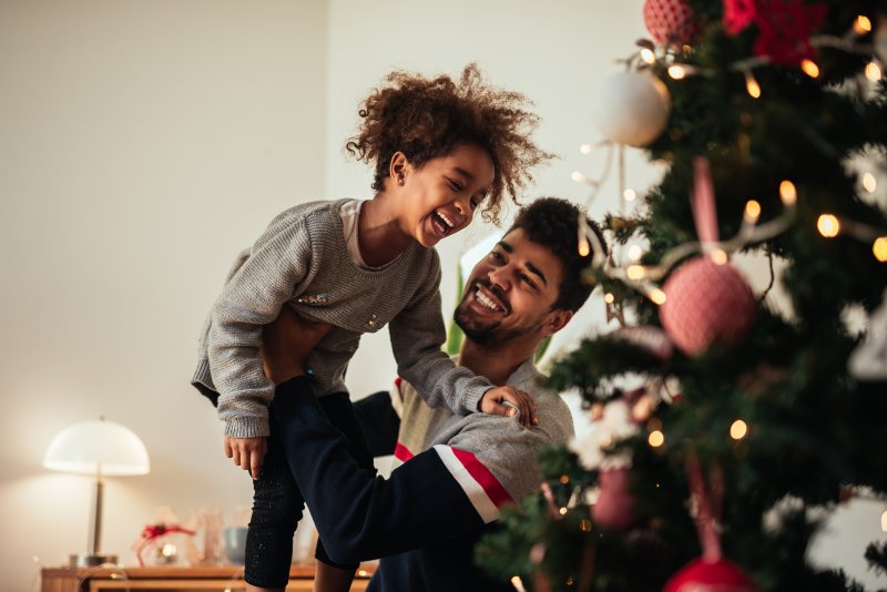 parent carrying child to top of Christmas tree