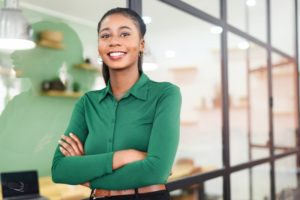 person standing in front of a window and smiling with their arms crossed